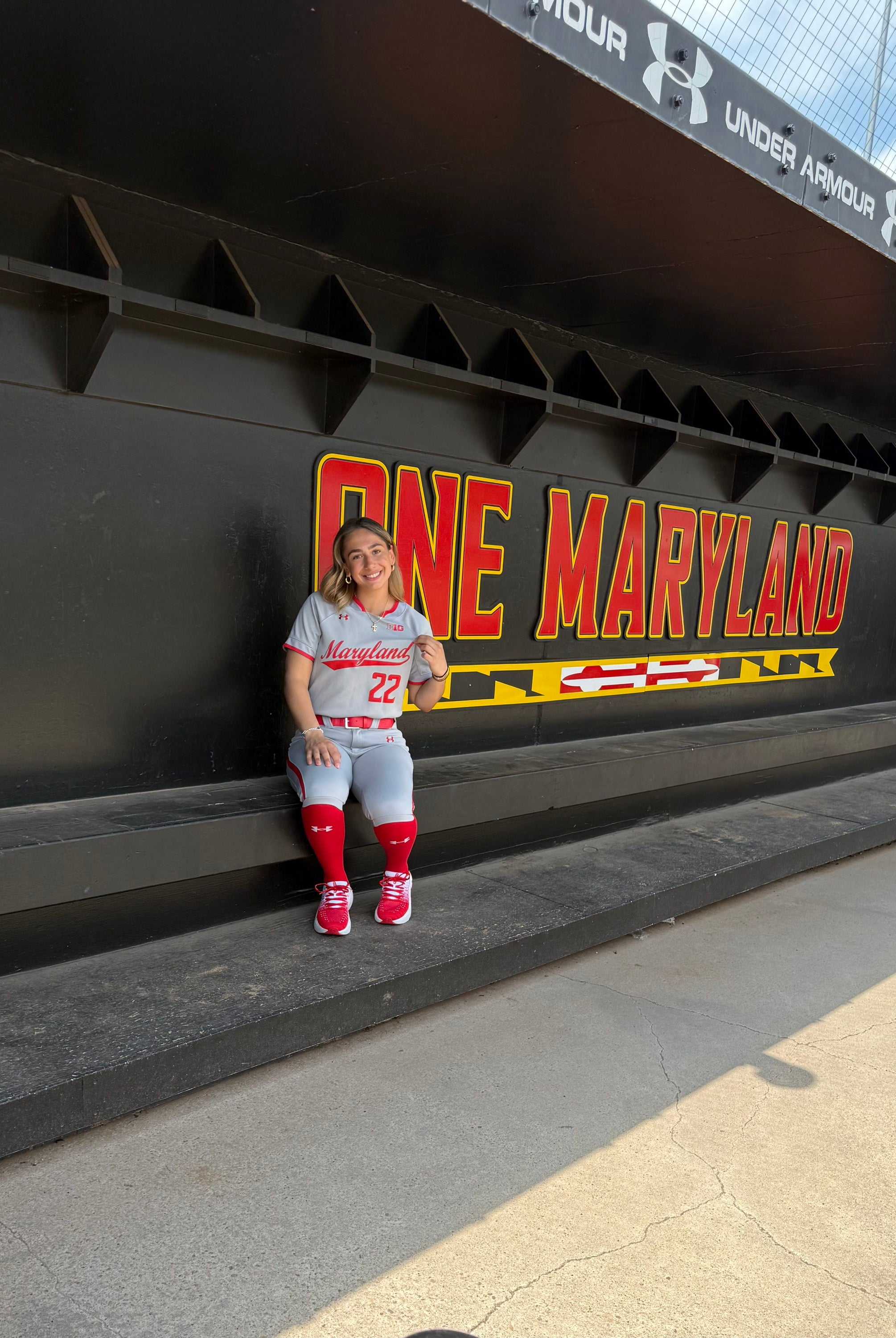 Person sitting on a bench by a wall with "ONE MARYLAND" written on it.