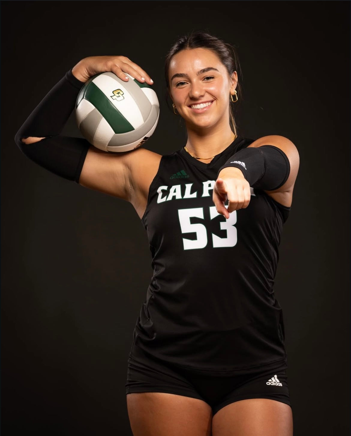 A volleyball player in a black uniform poses with a ball.