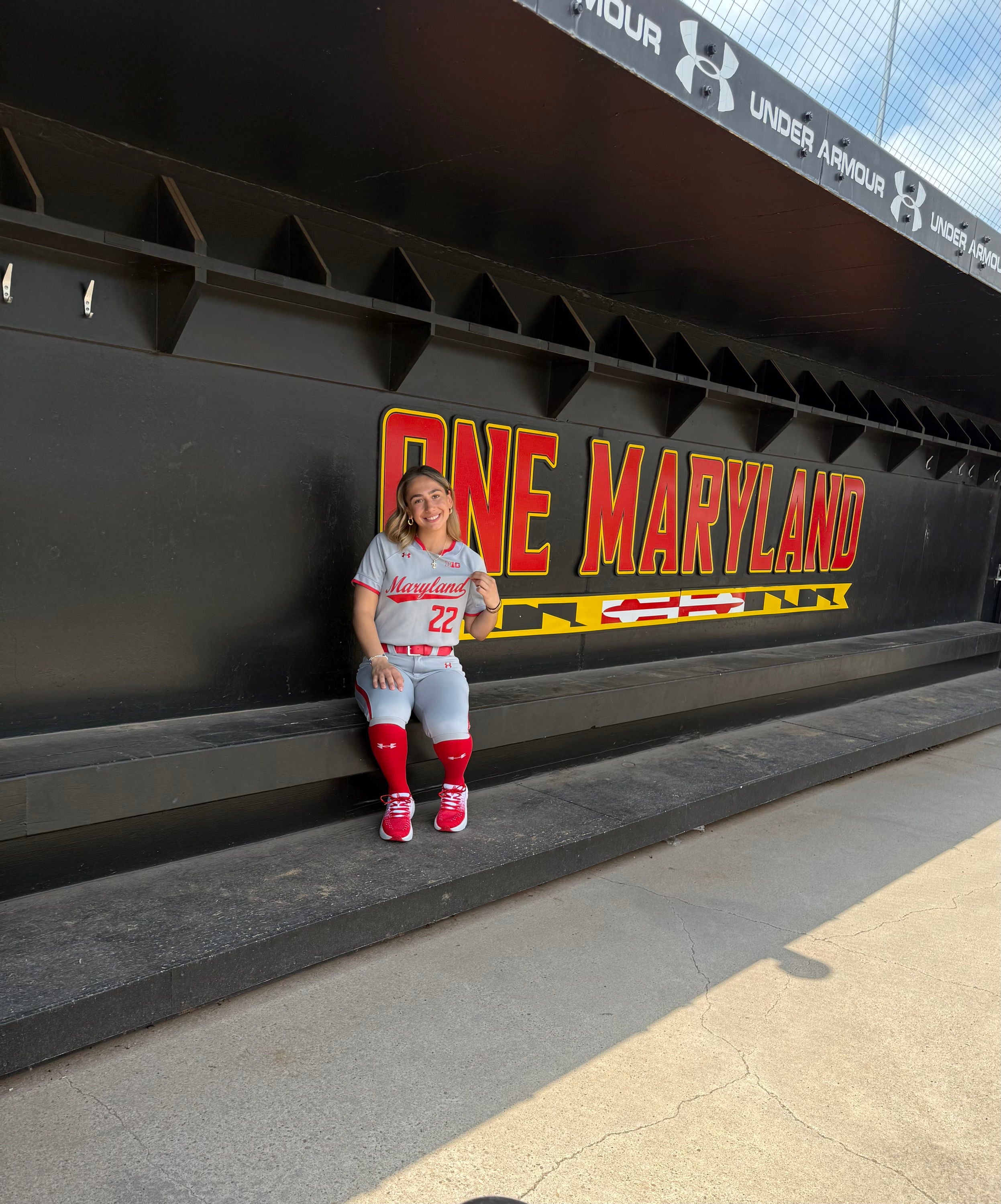Person sitting on a bench by a wall with "ONE MARYLAND" written on it.